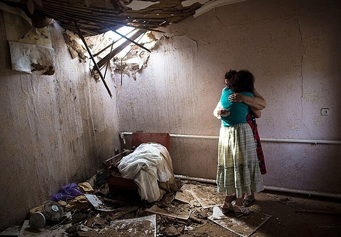 Hai phụ nữ ôm nhau khóc sau khi ngôi nhà của họ bị phá hủy bởi bom đạn. 