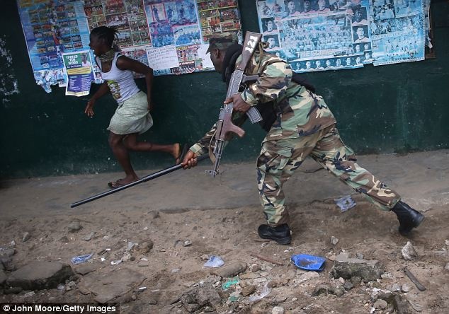 Binh sĩ thuộc quân đội Liberia, một phần của lực lượng đặc nhiệm chống Ebola, vung dùi cui vào một phụ nữ đang bỏ chạy tại khu ổ chuột West Point của Liberia hôm 20/8. 