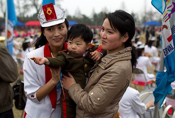 Một nữ nhân viên trong đội tuần hành đường phố chụp ảnh với cậu bé bên đường ở Bình Nhưỡng.