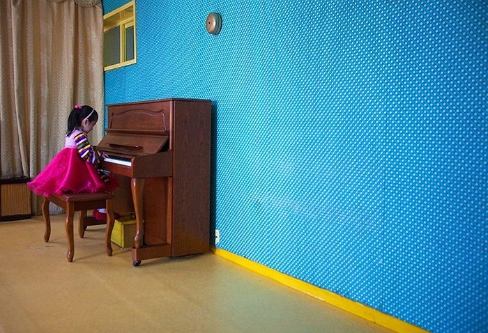 Một em nhỏ chơi đàn Piano ở trong lớp học Bình Nhưỡng.
