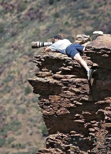 Một tay săn ảnh nhoài người trên vách núi để có thể 