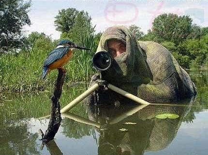 Một nhiếp ảnh gia trùm khăn kín đầu và ngâm người dưới hồ nước với ánh mắt đăm chiêu hướng vào đối tượng. 