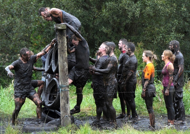 Mọi người giúp nhau vượt qua thử thách trèo qua hàng rào chướng ngại vật chăng đầy lốp xe. 