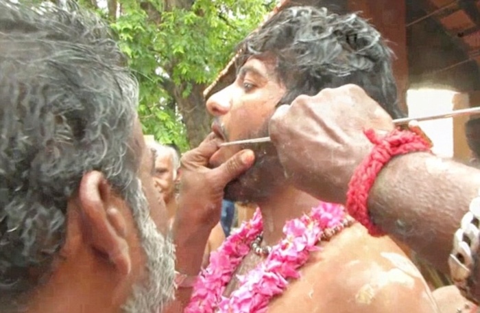 Người đàn ông chuẩn bị cho quá trình xuyên cây thép qua má trong lễ hội. 