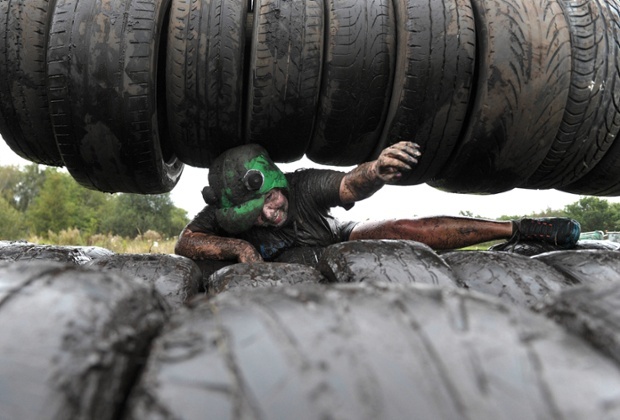 Cô gái đang cố gắng trèo lên lốp xe dính bùn.