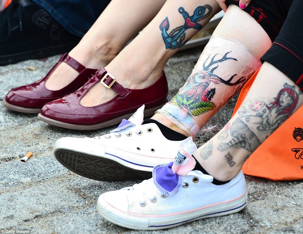 Các cô gái khoe hình xăm gần mắt cá chân. Một cô phải bọc ni lông để bảo quản hình mới xăm. Ảnh: Getty Images