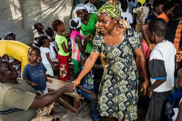 Người dân bắt tay chào nhau trong buổi lễ ở nhà thờ Dominion, sau khi khu vực được dỡ bỏ lệnh cách ly vào tháng 8/2014. Ảnh: NYT