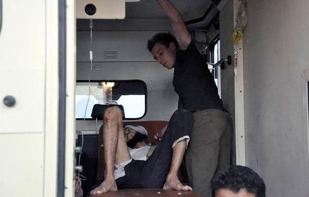 Abdul Rahman Kassig hỗ trợ chăm sóc y tế cho một người đàn ông bị thương tại Syria. Ảnh: Reuters