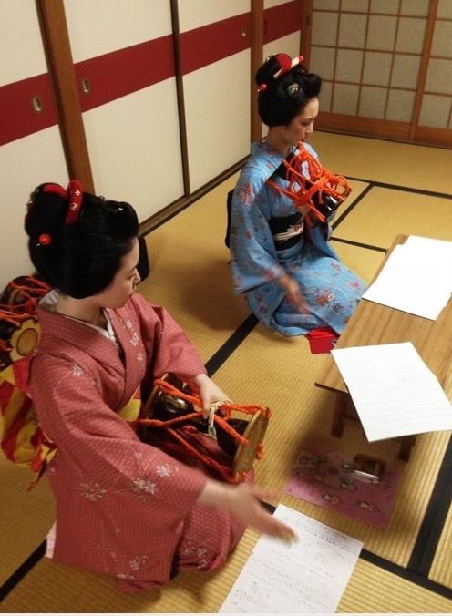 Cô Tomitsuyu (áo hồng) là một maiko, tức geisha thực tập. Cách đây một năm, cô từng là một thiếu niên chơi kèn trombone trong ban nhạc địa phương. Bây giờ cô đang học sử dụng một loại trống truyền thống.