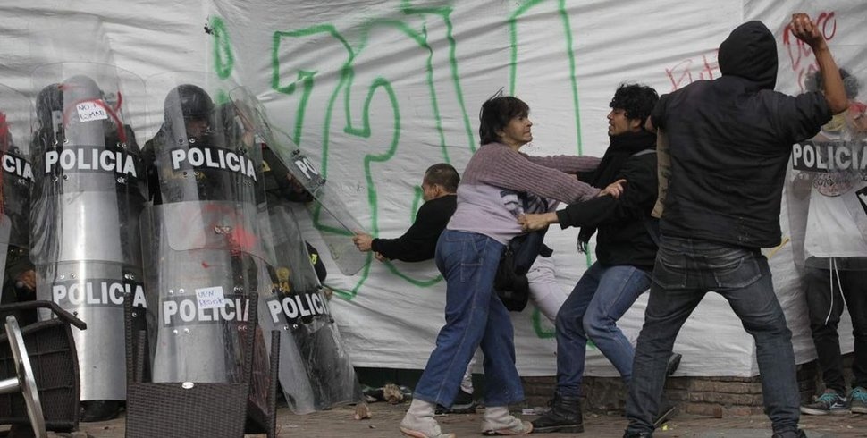Một người phụ nữ dũng cảm bảo vệ một nhóm cảnh sát chống bạo động trước sự giận dữ của đám đông quá khích tại thủ đô Bogotá, Colombia, năm 2013. 