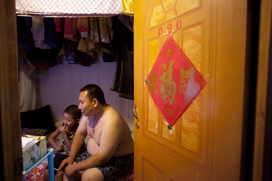 Anh Sun Kuangda, 29 tuổi, và con trai Xiang Song 8 tuổi đang xem truyền hình tại căn phòng trọ dưới một tầng hầm ở phía tây Bắc Kinh. Những người không đủ tiền thuê phòng trọ trên mặt đất mà phải tìm đến những căn phòng dưới tầng hầm thường là nhân viên bồi bàn, tiếp viên karaoke, thợ cắt tóc, đầu bếp, bảo vệ, công nhân, người giúp việc... Vào mùa hè, các căn phòng trở nên ẩm ướt và mốc meo.