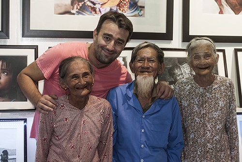 Nhiếp ảnh gia Réhahn Croquevielle bên gia đình ông bà Lê Văn Sẻ (91 tuổi) và bà Nguyễn Thị Lợi (83 tuổi, ngoài cùng bên phải) tại gallery tranh của Réhahn. Hai cụ sống đã gắn bó với nhau từ khi mới hơn 20 tuổi, sống chung 63 năm ở làng Trà Quế, cách thị trấn Hội An 3km. Ảnh: NVCC