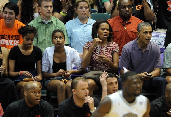 Tổng thống Obama cùng phu nhân và các con gái theo dõi một trận thi đấu bóng rổ giữa hai đội tuyển sinh viên. Ảnh: AFP