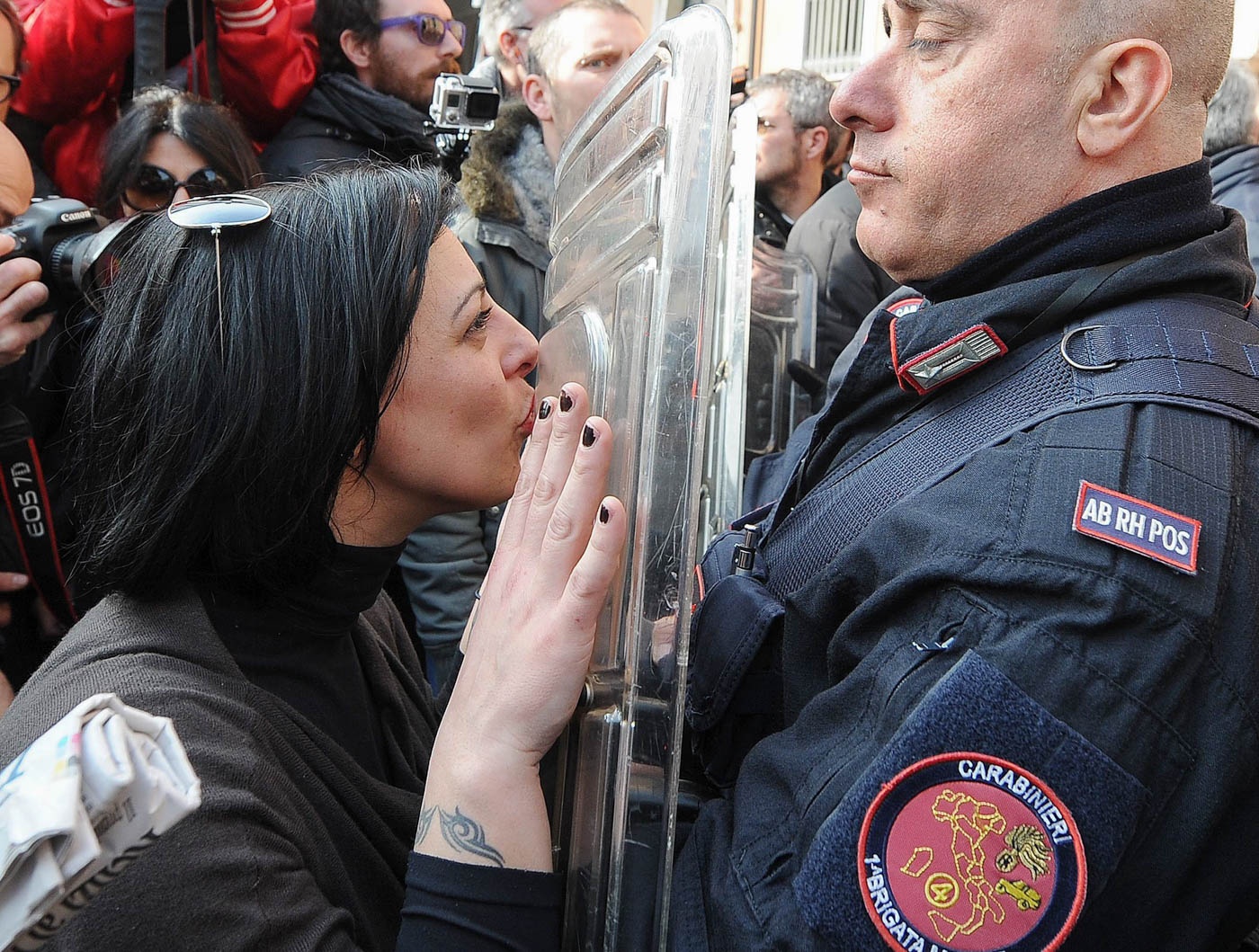 Một phụ nữ hôn lên tấm chắn của cảnh sát khi họ bảo vệ cho chuyến đi của Thủ tướng Italia, ông Matteo Renzi, đến một trường học ở Treviso ngày 26/2. Ảnh: EPA