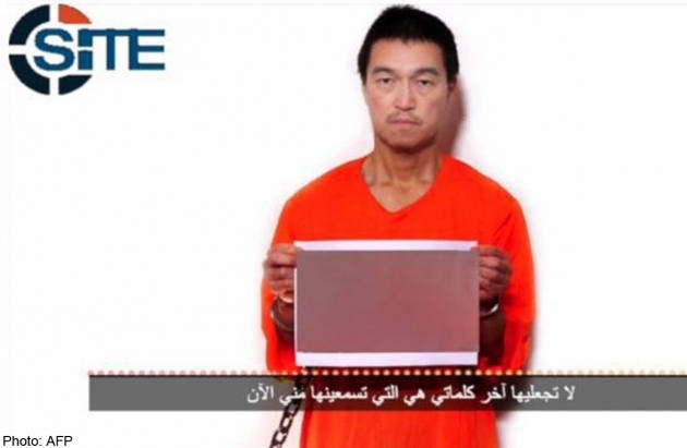 Con tin Kenji Goto cầm bức ảnh phiến quân hành quyết con tin Haruna Yukawa trong đoạn ghi âm.