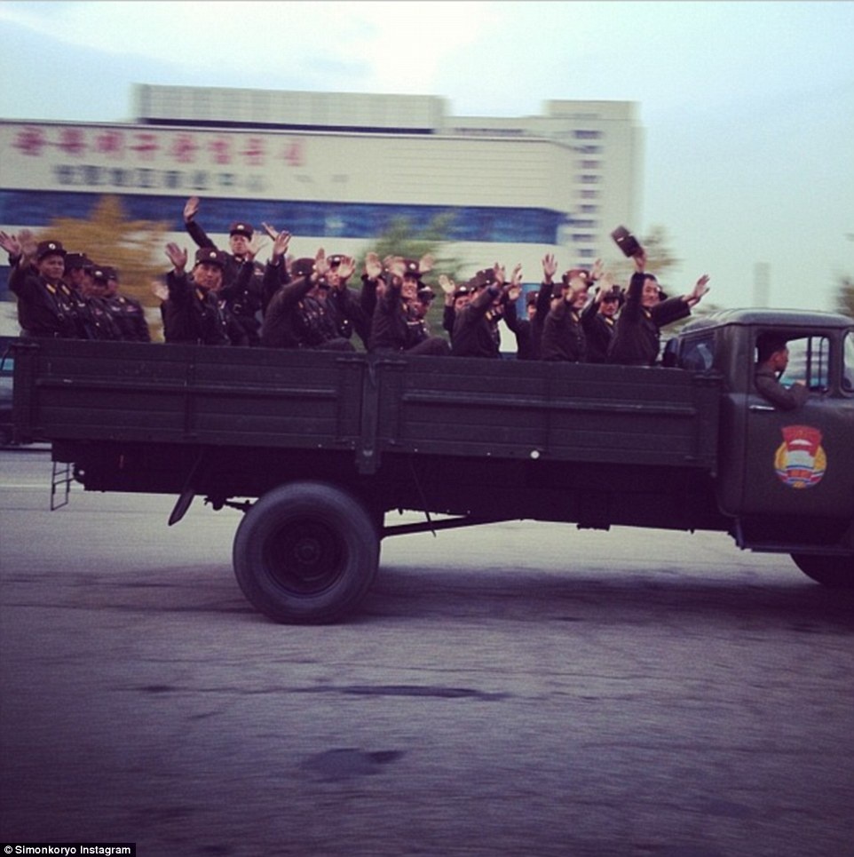 Các binh sĩ trên một xe quân sự vẫy tay cháo mọi người dân hai bên đường. 