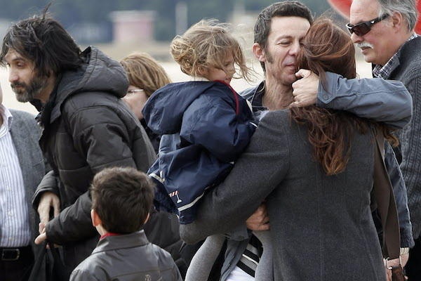 Nhà báo Javier Espinosa (thứ 2 từ phải qua) ôm vợ và con gái khi ông về đến sân bay quân sự ở Madrid, Tây Ban Nha vào ngày 30/3/2014. Người phát ngôn Bộ Ngoại giao Tây Ban Nha không phủ nhận, cũng không xác nhận nước này đã trả tiền chuộc theo yêu cầu của IS. Tuy nhiên, một phóng viên New York Times khi trao đổi với 3 con tin cho biết IS đã đề nghị Tây Ban Nha phải trả tiền chuộc để bảo đảm tính mạng cho các con tin. Ảnh: AP