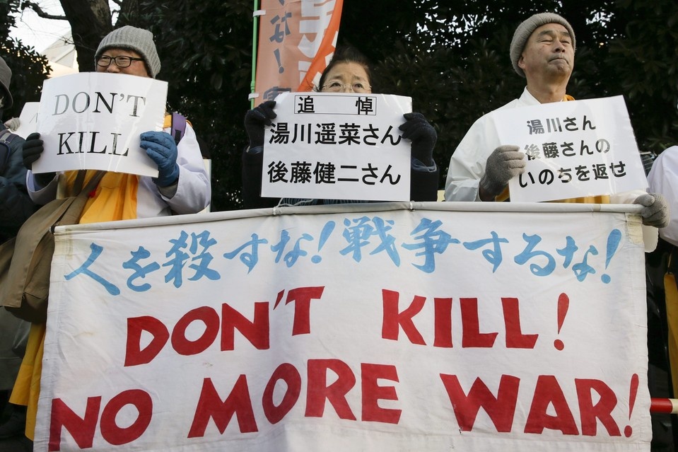 Những thầy tăng tham gia cuộc biểu tình phản đối chiến tranh cầm khẩu hiệu với dòng chữ: “Thương tiễn Haruna Yukawa và Kenji Goto” (ở giữa), “Hãy trả lại cuộc sống cho Yukawa và Goto” (bên phải). Ảnh: EPA