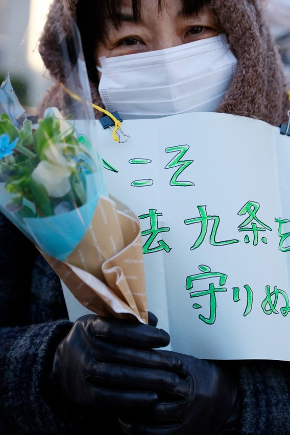 Một người phụ nữ cầm biểu ngữ: “Hiện tại là thời điểm chúng tôi cần bảo vệ điều số 9 trong Hiến pháp hơn bất cứ lúc nào”. Nội dung của điều 9 trong Hiến pháp của Nhật Bản cấm nước này tham gia các cuộc chiến”. Ảnh: Zuma Press