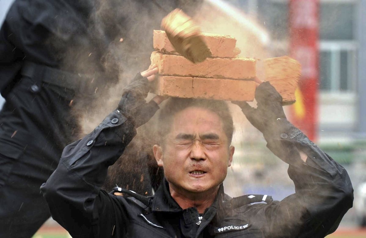 Tại cuộc diễn tập chống khủng bố ở quận Weng’an, tỉnh Quý Châu, Trung Quốc, năm 2012, một sĩ quan thuộc đội đặc nhiệm phản ứng nhanh (SWAT) dùng tay không chặt vỡ những viên gạch được đặt trên đầu của đồng đội. 