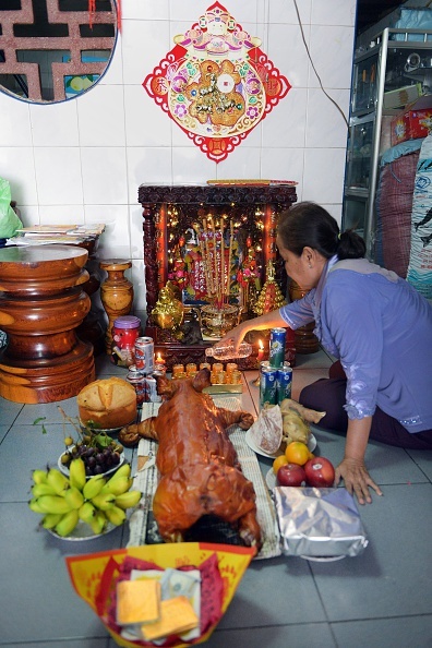 Một phụ nữ sống ở Phnom Penh, Campuchia, chuẩn bị lễ vật gồm heo quay, hoa quả để cúng tổ tiên trong ngày 18/2. 