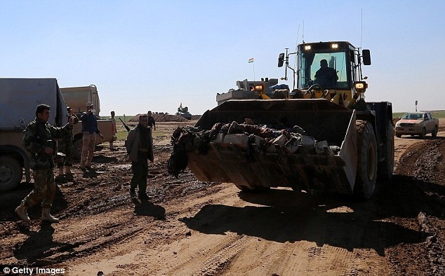 Người Kurd sử dụng máy đào để dọn thi thể chiến binh IS. Ảnh: Daily Mail