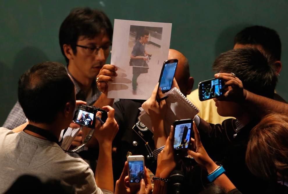 Một nhà báo cầm ảnh của một hành khách mà cảnh sát Malaysia khẳng định đã dùng hộ chiếu giả để bước lên chuyến bay MH370. Khi đó, giới chức Malaysia không loại trừ khả năng máy bay bị không tặc. Ảnh: Reuters