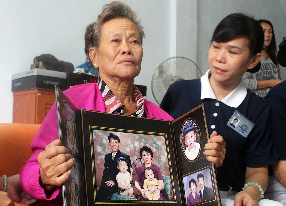 Bà Suharni (người Indonesia) cầm ảnh con trai và vợ của anh. Con trai và con dâu của bà đều là hành khách trên MH370. Ảnh: AFP