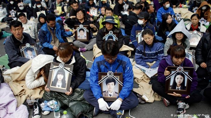 Nhiều người giữ chặt tấm ảnh người thân và ngồi trên một con đường gần Phủ 