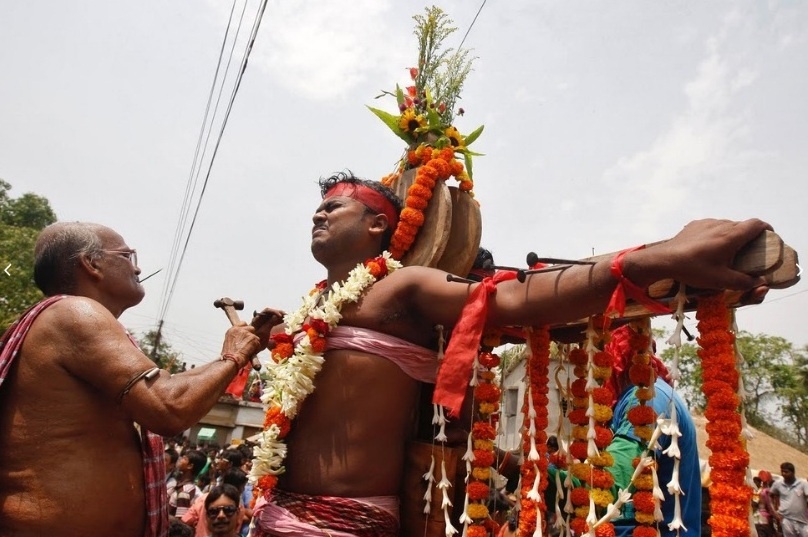 Một chức sắc tôn giáo đang đóng đinh xuyên qua cánh tay của một người mộ đạo. Họ mong muốn thần Shiva trong đạo Hindu sẽ đáp ứng những lời cầu nguyện.