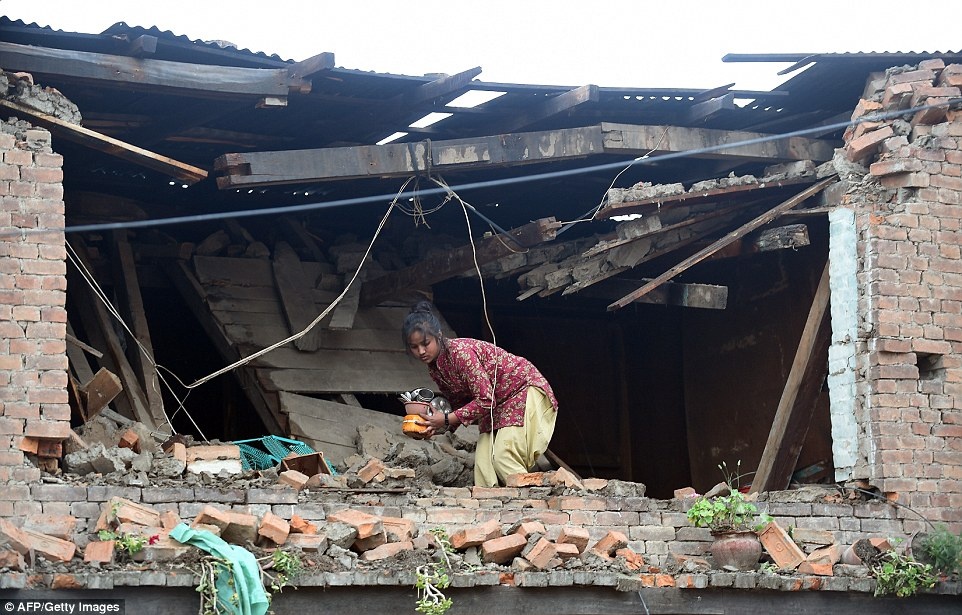 Một bé gái mang nồi và chảo khỏi ngôi nhà tan hoang ở Bhaktapur, ngoại ô thủ đô Kathmandu. Ảnh: AFP
