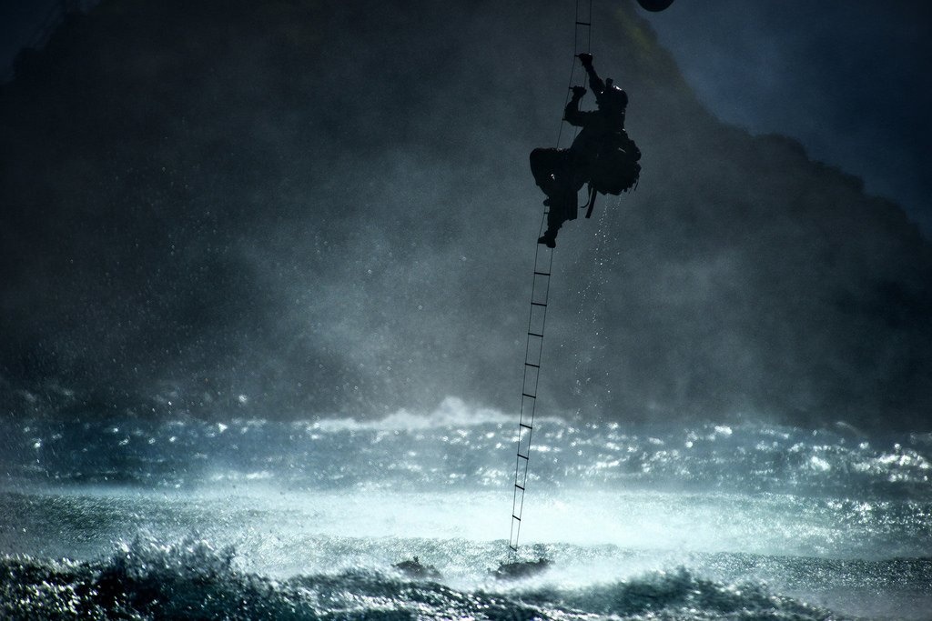 Một thành viên của đội chiến thuật đặc biệt số 22 leo thang lên trực thăng CH-47 Chinook khi nó đang bay qua đại dương, ngày 20/6/2014. 