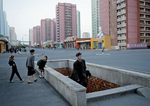 Người dân Bình Nhưỡng di chuyển xuống hầm đi bộ trong khi một nữ cảnh sát đang làm nhiệm vụ tại một ngã tư vắng vẻ.