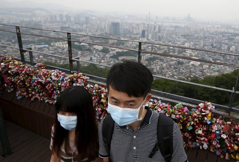 Hai thanh niên đeo khẩu trang di chuyển trên một cây cầu ở thủ đô Seoul trong ngày 