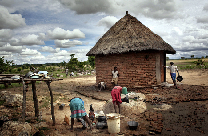 Những đứa trẻ bên ngoài túp lều của ông Mambidzeni, 91 tuổi và bà Zemba, 75 tuổi. Ông bà có 14 con. 10 trong số họ đã chết. Hiện họ nhận chăm sóc thêm 9 đứa trẻ nhiễm mồ côi AIDS ở tuổi từ 8 đến 16.