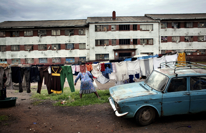 Một người phụ nữ phơi quần áo gần xe ôtô cũ tại khu Mbare, thủ đô Harare. Những căn hộ tại khu vực này khá đông. Nhiều nhà là nơi sinh sống của hai hoặc 3 hộ gia đình.