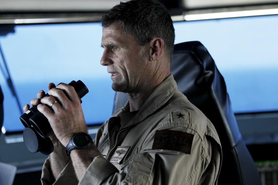 Chuẩn Đô đốc Andrew Lewis dùng ống nhòm để quan sát hoạt động trên tàu sân bay từ trung tâm chỉ huy.