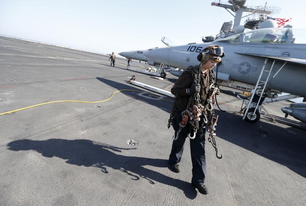 Một nhân viên trên tàu sân bay đeo những sợi dây móc trên vai. Họ dùng chúng để cố định vị trí các tiêm kích trên sàn USS Theodore Roosevelt. 