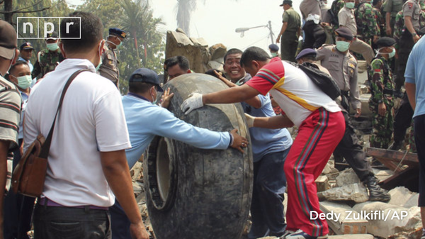 Những người đàn ông di chuyển bánh xe của chiếc phi cơ để tìm người bị vùi bên dưới. 