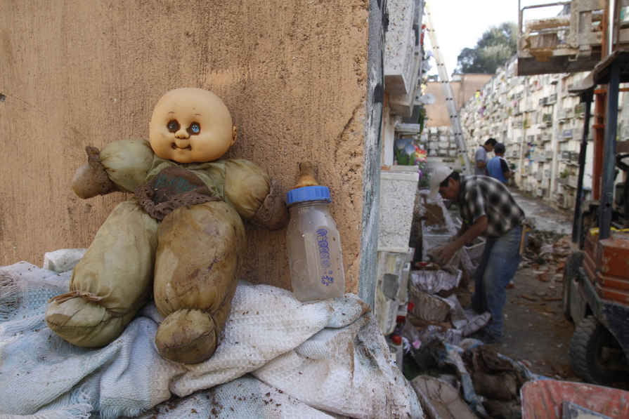  Một phu bốc mộ đựng thi hài của trẻ sơ sinh vào túi nhựa trước khi chuyển tới ngôi mộ tập thể. 