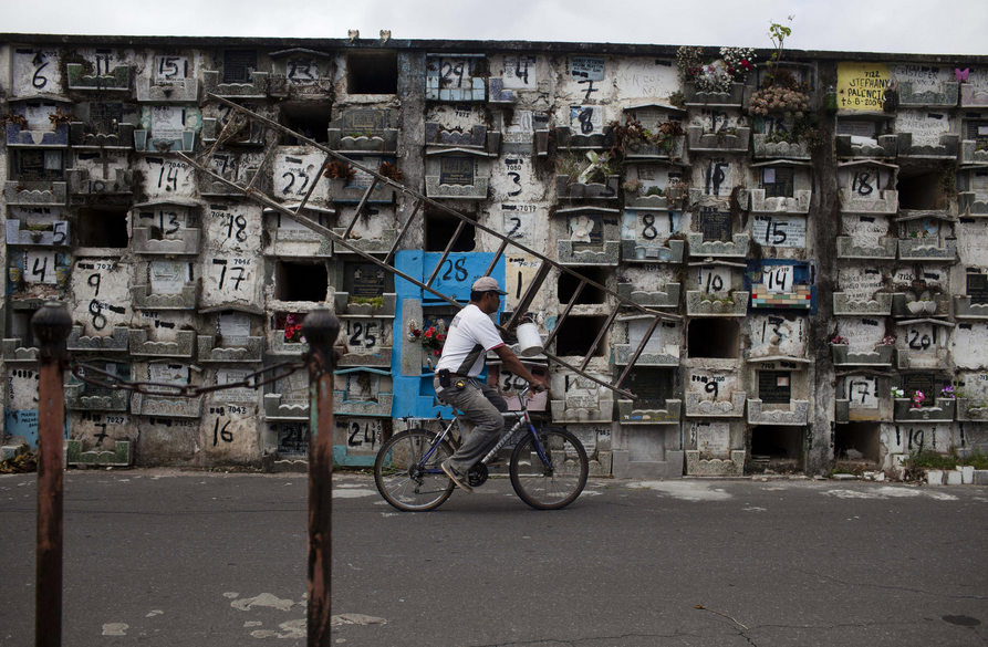 Một người đàn ông lái xe qua những ngôi mộ của trẻ sơ sinh được đánh số trước khi khai quật.