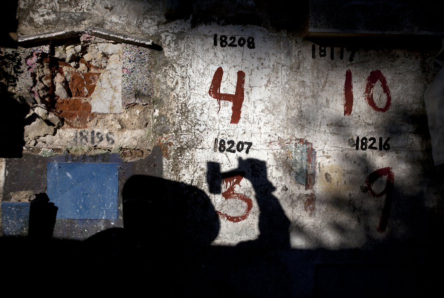 Bóng in hình một người đàn ông dùng búa đập những mảng xi măng để đưa các thi hài ra ngoài.