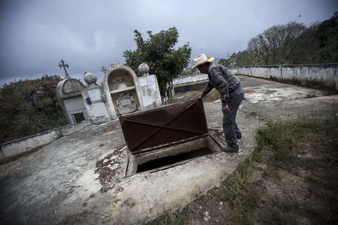 Người đàn ông mở nắp một ngôi mộ tập thể.