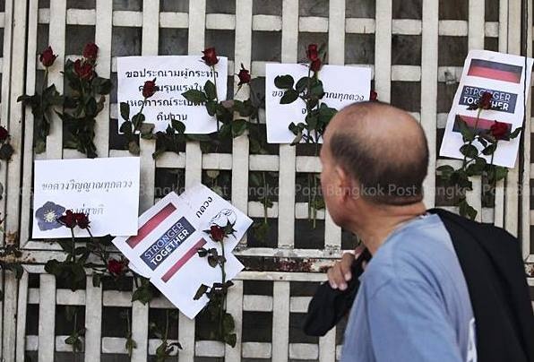 Một người đàn ông nhìn những tấm thiệp và hoa tưởng niệm các nạn nhân thiệt mạng sau vụ nổ được gắn trên hàng rào tại giao lộ  Ratchaprasong. Ảnh: Twitter