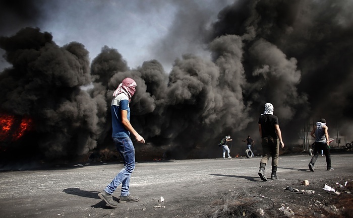 Người biểu tình Palestine đốt lốp xe rồi ném đá vào lực lượng an ninh Israel trong cuộc đụng độ tại thị trấn Al-Bireh ở Bờ Tây. Tổng thư ký Liên Hợp Quốc Ban Ki Moon đã tới Jerusalem tuần này để thảo luận với nhà lãnh đạo Israel và Palestine nhằm chấm dứt tình trạng bạo lực tại đây. Ảnh: AFP
