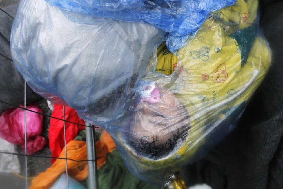 Một em nhỏ ngủ khi được cuộn trong áo mưa tại biên giới Slovenia – Croatia ngày 19/10. Ảnh: Reuters