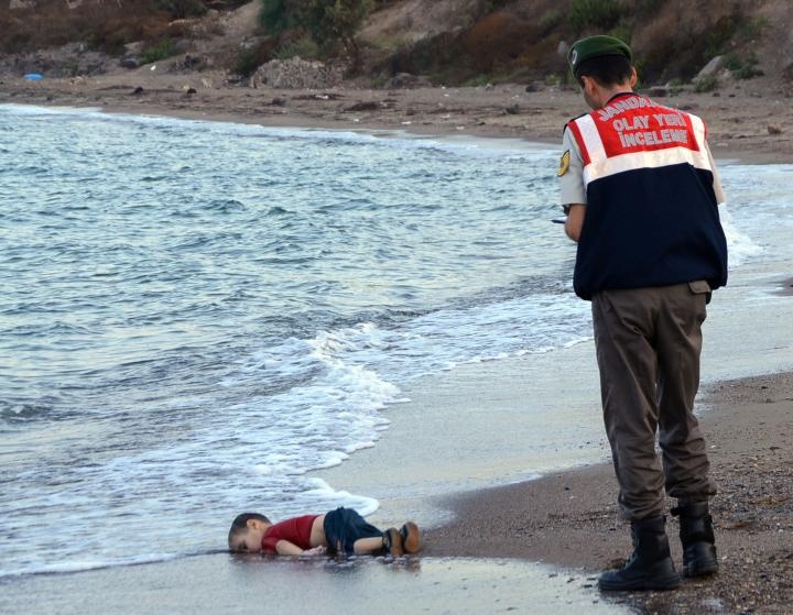 A paramilitary police officer investigates the scene before carrying the lifeless body of Alan Kurdi, 3, after a number of migrants died and others were reported missing when boats carrying them to the Greek island of Kos capsized near the Turkish resort of Bodrum on Sept. 2, 2015.