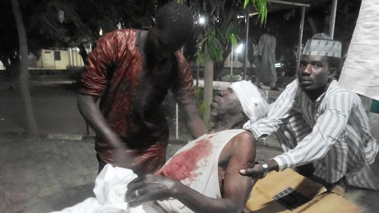 Men attend to their father in an emergency room after a suicide attack at a mosque in Kano, Nigeria, that killed more than 100 people in November 2014.