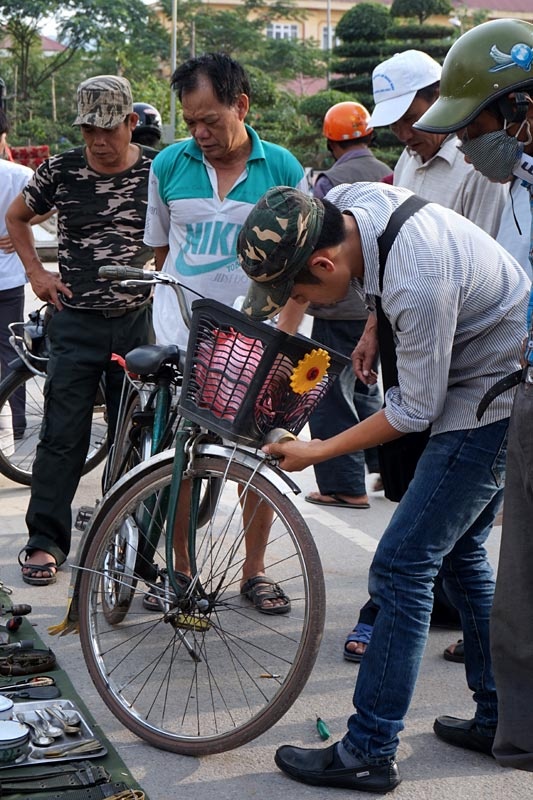 Một người đàn ông tháo chiếc đèn trên xe peugeot của mình bán giữa chợ.