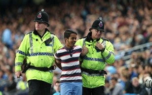 Mặc dù bị các nhân viên an ninh dẫn giải ra khỏi sân nhưng CĐV này vẫn nở nụ cười mãn nguyện.